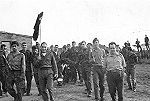 Furriel Serôdio segura a bandeira. À direita, o 1º Sarg. Duarte e atrás dele o Alf. Duarte. Ao centro, a coroa de flores para a sepultura. Foto de Vítor Duarte, Quixico 1971