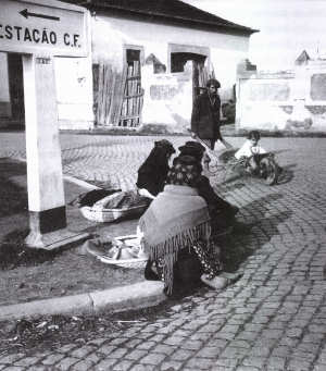 Mulheres sentadas no lancil do passeio à espera da camioneta.